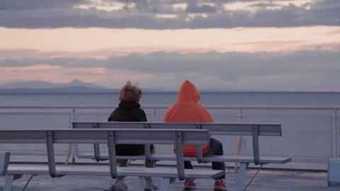 Two people ,no faces, sitting on the deck of a ferry watching sunset, ocean view Stock Footage 258808139
