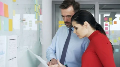 Two people at office planning new business strategy on whiteboard Stock Footage 73673376