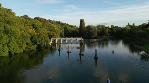 Two people paddleboard on a calm river with a dam and lush green trees in t.. Stock Footage 340513737