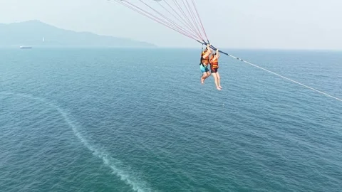 Two people parasailing over the blue ocean on a clear summer day, suspended Video stock 333376315