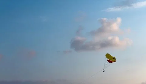 Two people parasailing with a parachute pulled by a boat on vacation at sunse Stock Photos