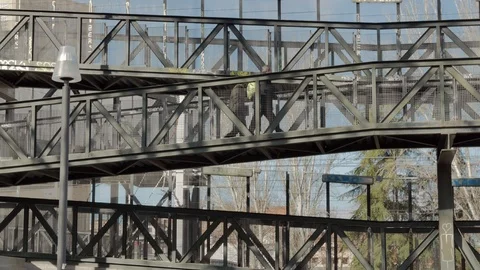 Two people pass through an elevated metal walkway in an industrial area Stock Footage 101728239
