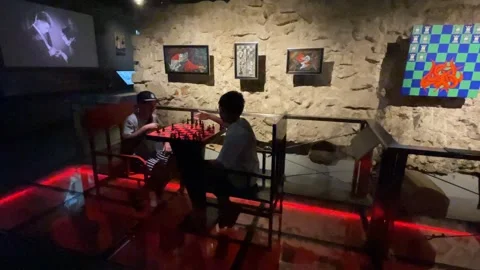 Two people playing chess in dimly lit museum setting with digital screens a.. Stock Footage 314507964