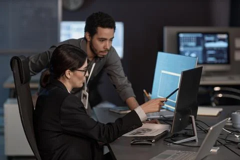 Two people pointing at computer screen while working in IT company Stockfoto's