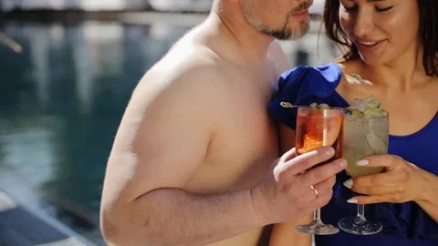 Two people at poolside drinking fresh cold beverages. Ccocktails in the hands Stock Footage 268233242