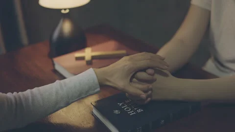 Two people praying together while holding hands, showing faith, trust, hope.. Video stock 340621094