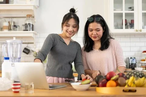 Two people preparing fresh fruit in a modern kitchen while checking a recip.. Stock Photos
