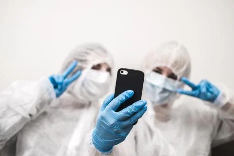 Two people in protective white translucent suit, blue rubber gloves, medical Stock Photos