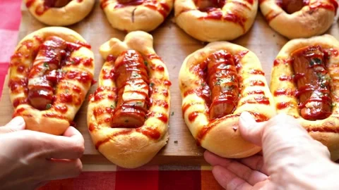 Two people reaching for a delicious sausage bun on the table Stock Footage 335784341