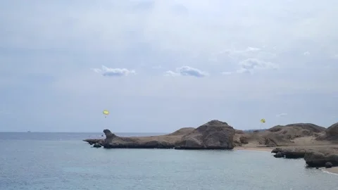 Two people ride a parachute in the red sea. The speedboat is pulling a blue and Stock Footage 236570790