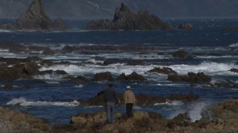 Two people on the rocks looking out to sea Stock Footage 8680786