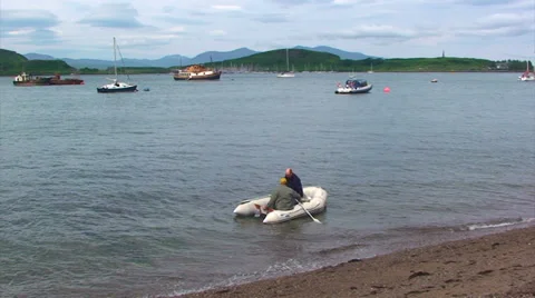 Two people rowing on a boat from the beach to yacht Stock Footage 39560967
