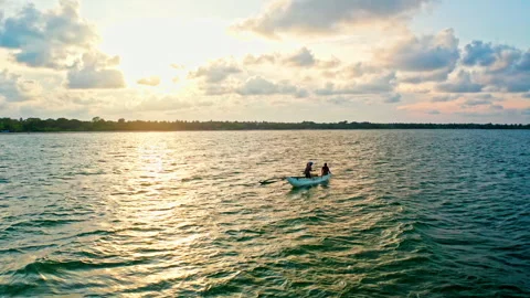 Two people rowing a boat on a lagoon at golden hour Stock Footage 337915640