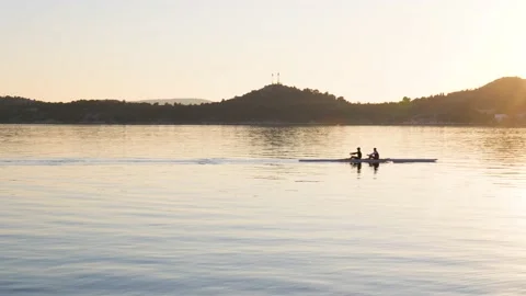 Two people rowing a canoe or rowboat in the sea during sunset Stock-Footage 231165034