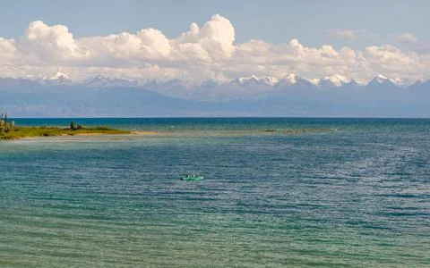 Two people rowing in a small boat on tranquil Issyk-Kul lake Stock Photos