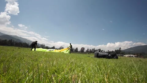 Two people saving the parachute after a paraglide in a green grass field Vídeo Stock 133379681