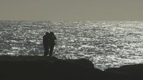 TWO PEOPLE SILHOUETTED AGAINST AN OCEAN VIEW ON BLUFF; MEDIUM Stock Footage 59070830