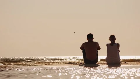 Two people silhouetted sitting on beach watching ocean waves at sunset peac.. Stock-Footage 334848952