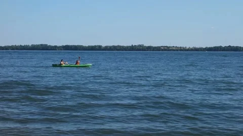 Two people sit and row in a kayak on the lake Stock Footage 138012595