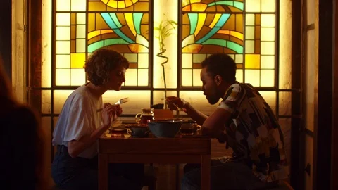 Two people sit at a table in a cafe, girl take a plate to try food Stock Footage 121941002