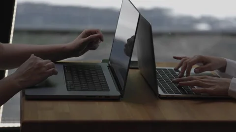 Two people sit at table with laptops typing on keyboard working. Persons typing Video stock 277772733