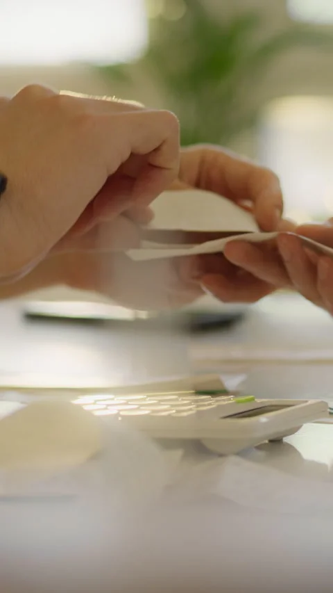 Two people sit at a well-lit table in a bright office sorting papers and oth Stock Footage 341284895