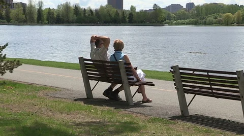 Two people sitting on bench by the lake Stock Footage 47722552