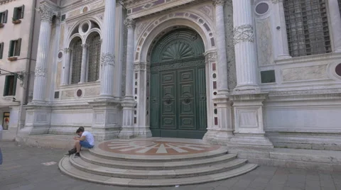 Two people sitting down in front of Scuola Grande di San Rocco, Venice Stock Footage 57176349