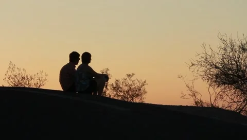Two people sitting on hillside at dusk in Mazatlan, Mexico Stock Footage 6093936