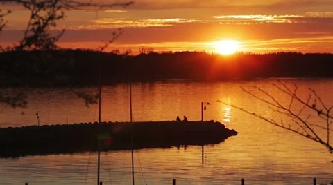 Two people sitting on pier at sunset Stock Footage 37227288