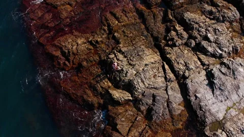 Two People Sitting On Rocks Along Ocean Stock Footage 196741352