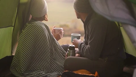 Two people sitting in tent looking at landscape enjoying tea from thermos Video stock 100723816