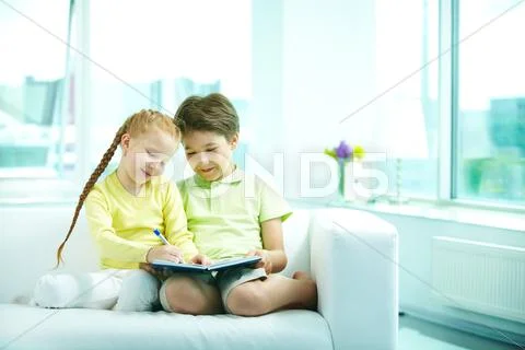 Two people sitting together on sofa and writing in a textbook Stock Photos