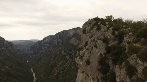 Two people sitting on the top of a cliff over a rocky gorge and a river, France Stock Footage 100551253