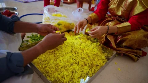 Two people sort marigolds on tray for ceremony indoor Stock Footage 304500023