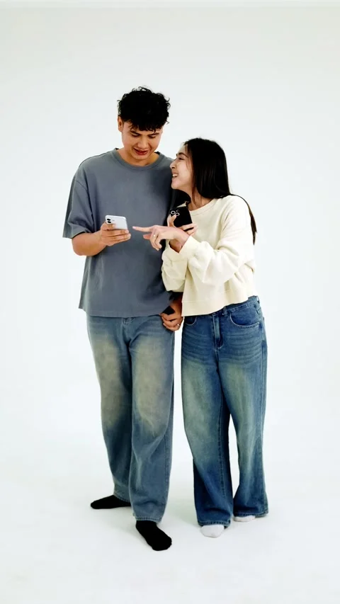 Two people stand back-to-back, each absorbed in their smartphone 動画素材 327122832