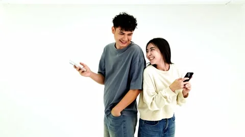 Two people stand back-to-back, each absorbed in their smartphone Stock Footage 328076878