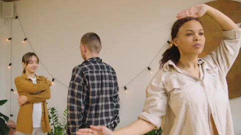 Two people stand facing each other in a bright room. They are engaging in a comm Video stock 346148142