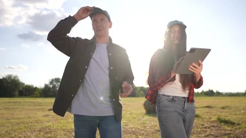 Two people standing in field with tablet. Woman and man working in a lifestyle Stock Footage 316686537
