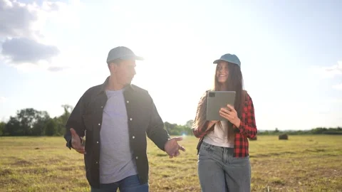 Two people standing in field with tablet. Woman and man working in a field with Stock Footage 318490138
