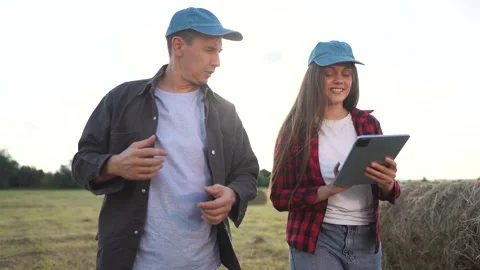Two people standing in field with tablet. Woman and man working in a field with Stock Footage 320060975