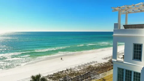 Two people strolling down a private beach next to a luxury home Stock Footage 239078655