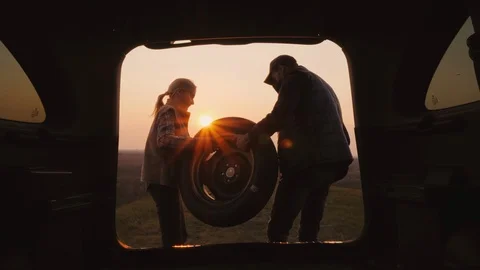 Two people take the spare tire out of the trunk Stock Footage 106874258