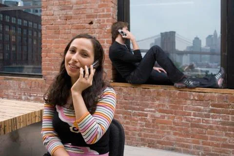 Two people talking on mobile phones in a modern apartment Stock Photos