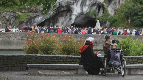 Two people talking, praying at Grotto Massabielle in Lourdes, France Stock Footage 86758688