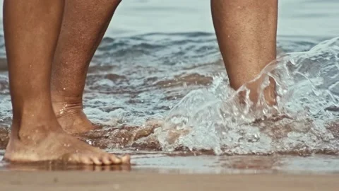 Two people with their bare feet walk along sandy beach by sea, close up shot of Stock-Footage 296228705