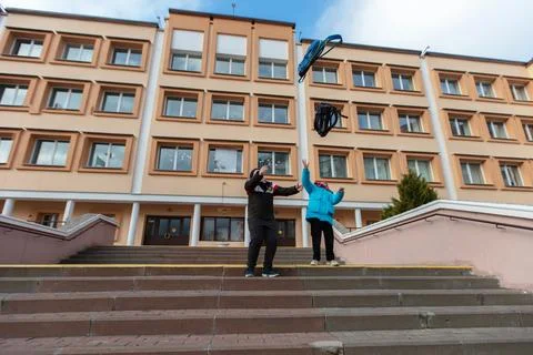 Two people throw a blue object from the stairs of a large building during t.. Stock Photos