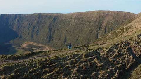 Two people on the top of mountain looking inside caldera of greate volcano of 스톡 동영상 117305689