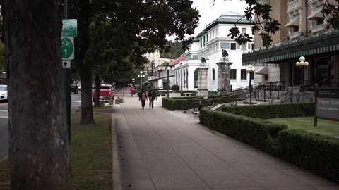 Two people walk down sidewalk of at bath house row in Hot Springs AK Stock Footage 113731435