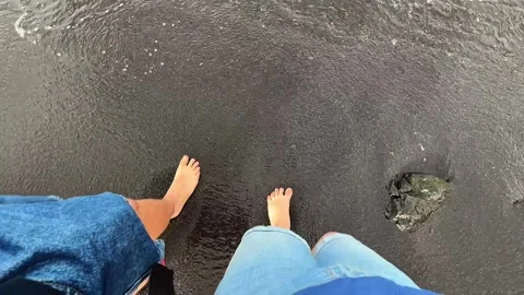 Two People Walking Barefoot Toward the Ocean on a Dramatic Black Sand Beach Stock Footage 324705257